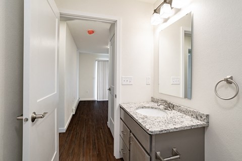 a bathroom with a sink and a mirror and a hallway