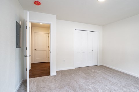 an empty living room with white walls and a door to a hallway