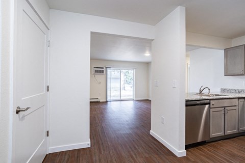 an empty kitchen and living room with wood flooring and white walls