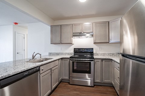 an empty kitchen with stainless steel appliances and granite counter tops
