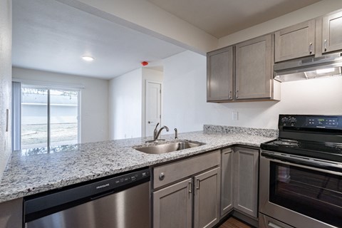 an empty kitchen with granite counter top and stainless steel appliances