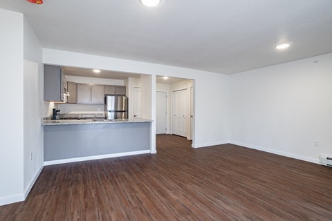 the living room and kitchen of an empty apartment with wood flooring
