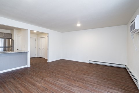 an empty living room with wood floors and white walls