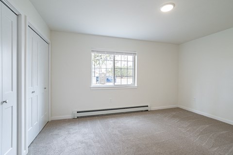 an empty room with a window and white walls