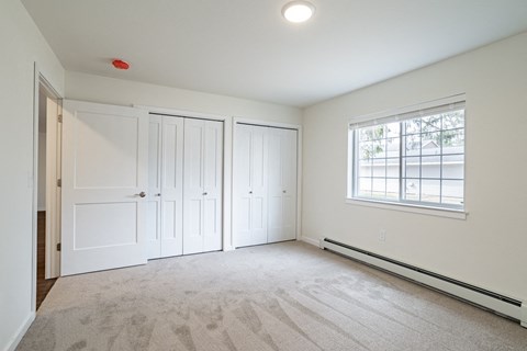 an empty bedroom with white walls and white doors and a window