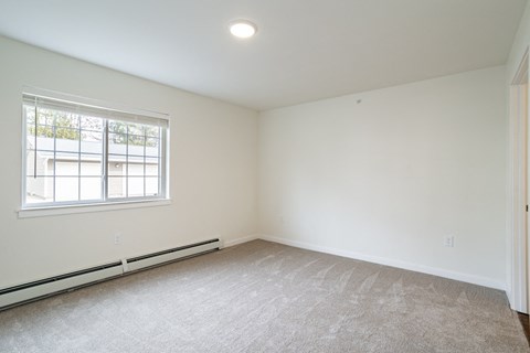 the living room of an empty home with white walls and a window
