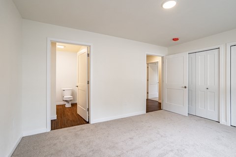 a bedroom with white doors and a bathroom with a toilet
