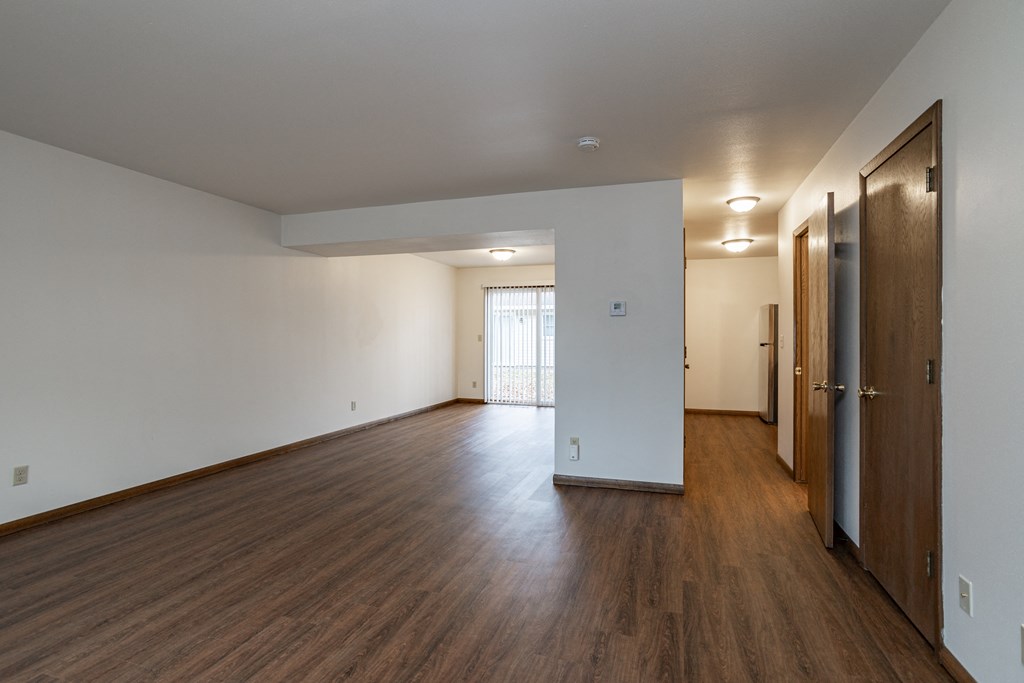 an empty living room with wood floors and white walls