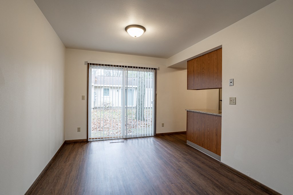 an empty living room with a sliding glass door to a balcony