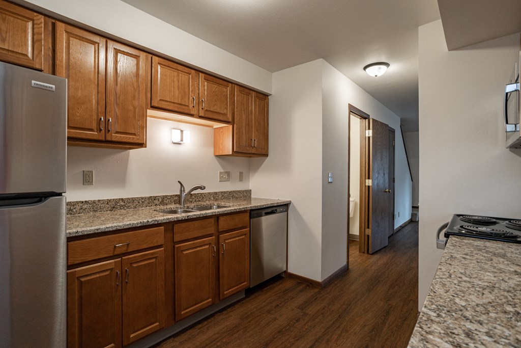 a kitchen with wood cabinets and granite counter tops and a stainless steel refrigerator
