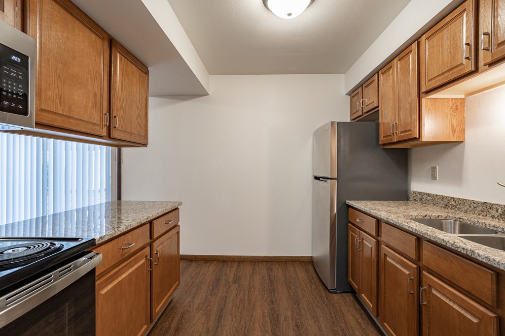 a kitchen with wood cabinets and granite counter tops and a stainless steel refrigerator
