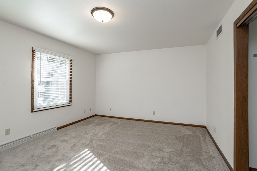 an empty living room with a window and carpet