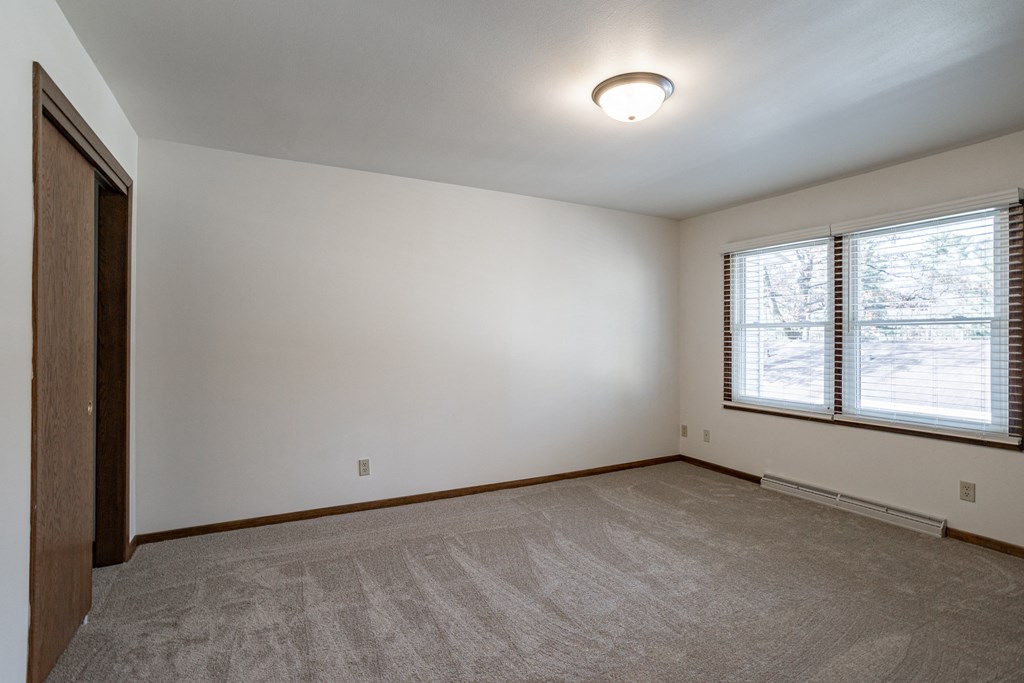 the living room of an empty house with carpet and a window