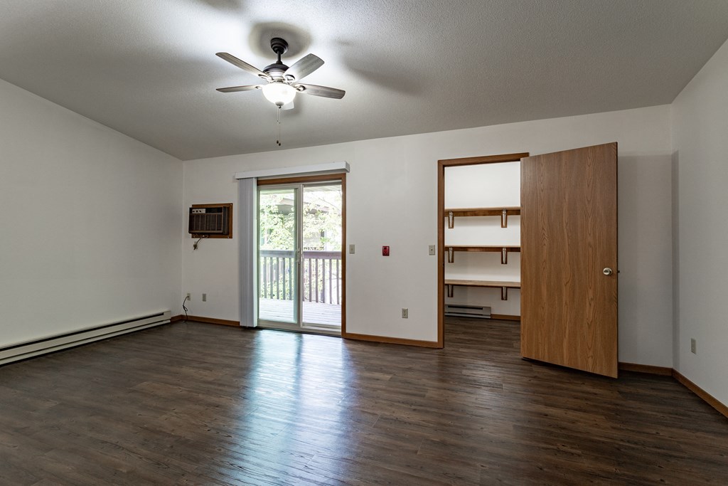 an empty living room with wooden floors and a ceiling fan