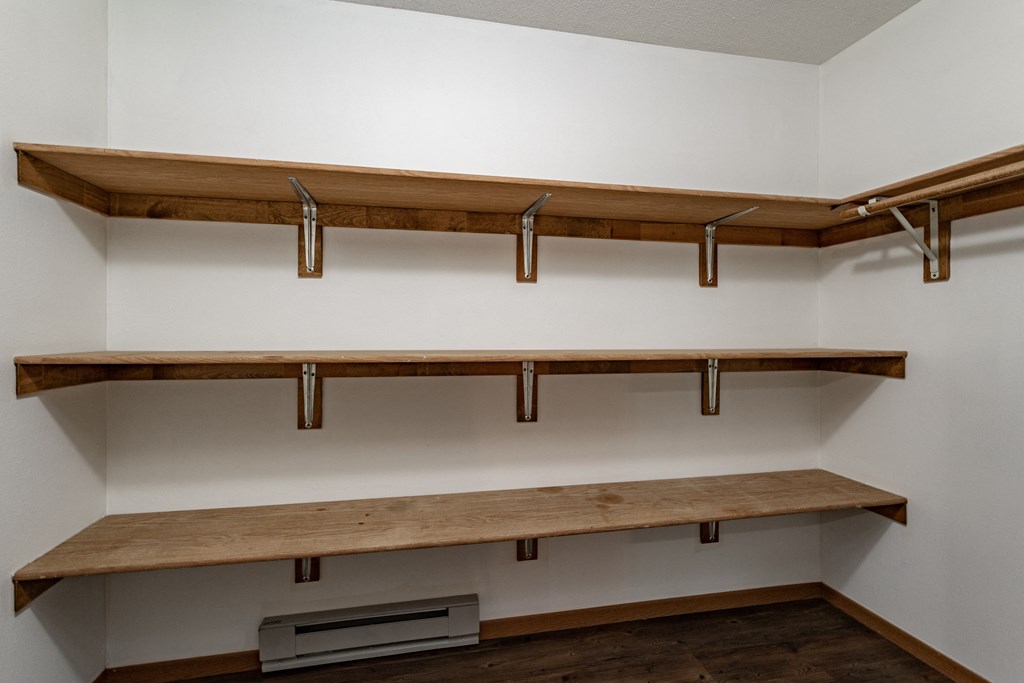 a walk in closet with wooden shelves and a wall mounted shelf