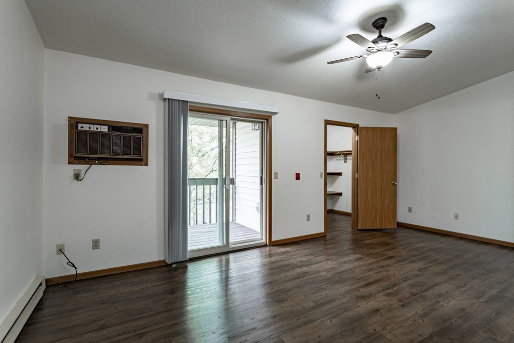an empty living room with a sliding glass door and a ceiling fan