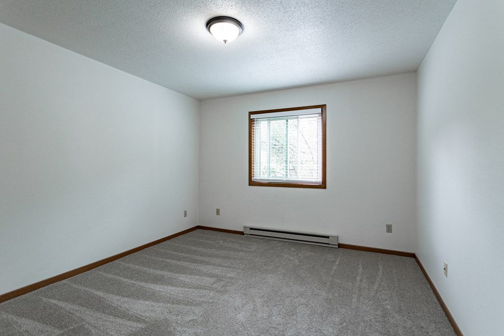 the living room of an empty house with white walls and a window
