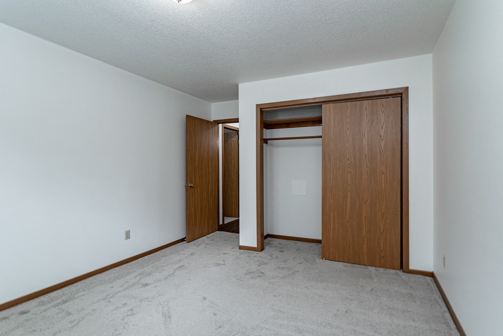 an empty living room with white walls and a door to a closet