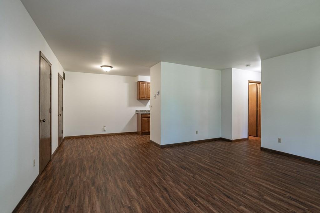 an empty living room with wood flooring and white walls