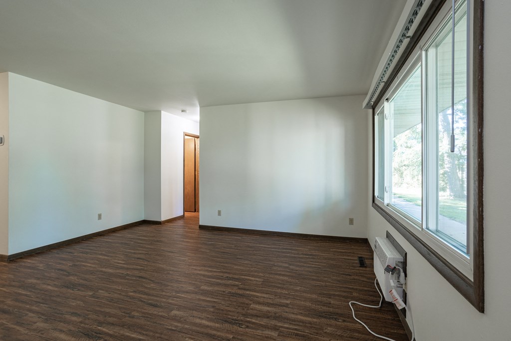 an empty living room with white walls and a large window