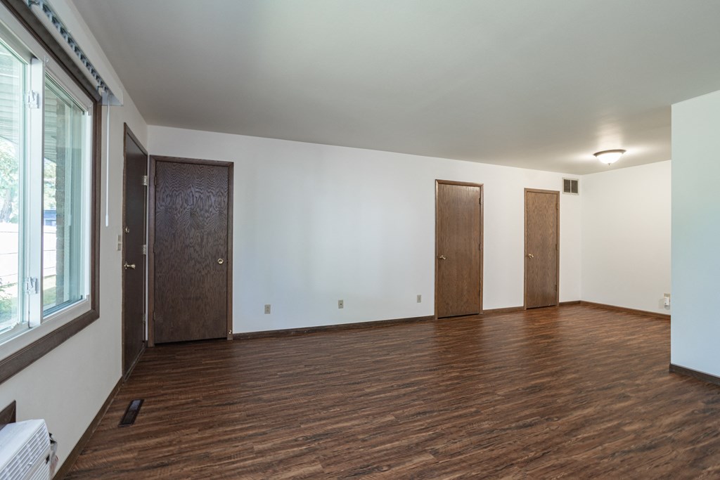 an empty living room with wood flooring and two doors