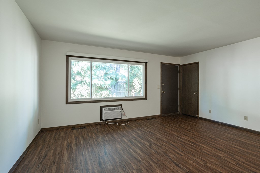 an empty living room with a large window and wooden floors