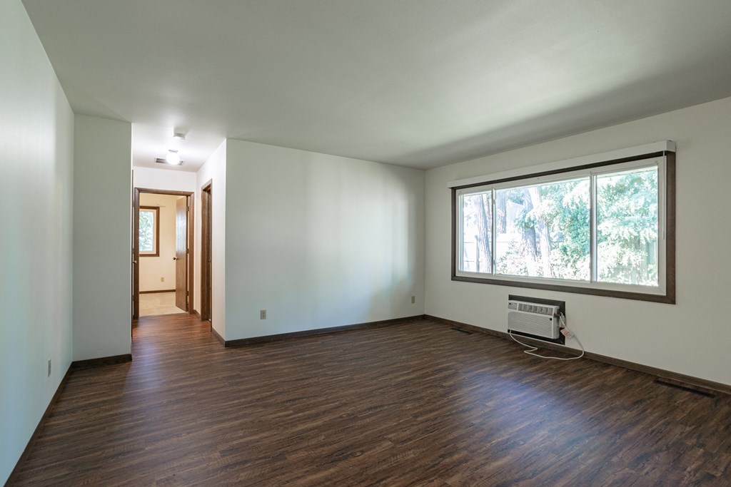 an empty living room with wood floors and a large window
