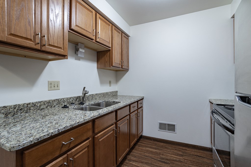 a kitchen with granite counter tops and wooden cabinets and a sink