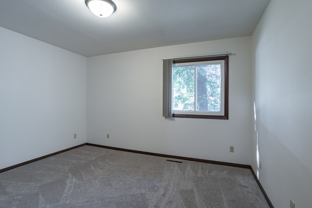 an empty living room with a window and white walls