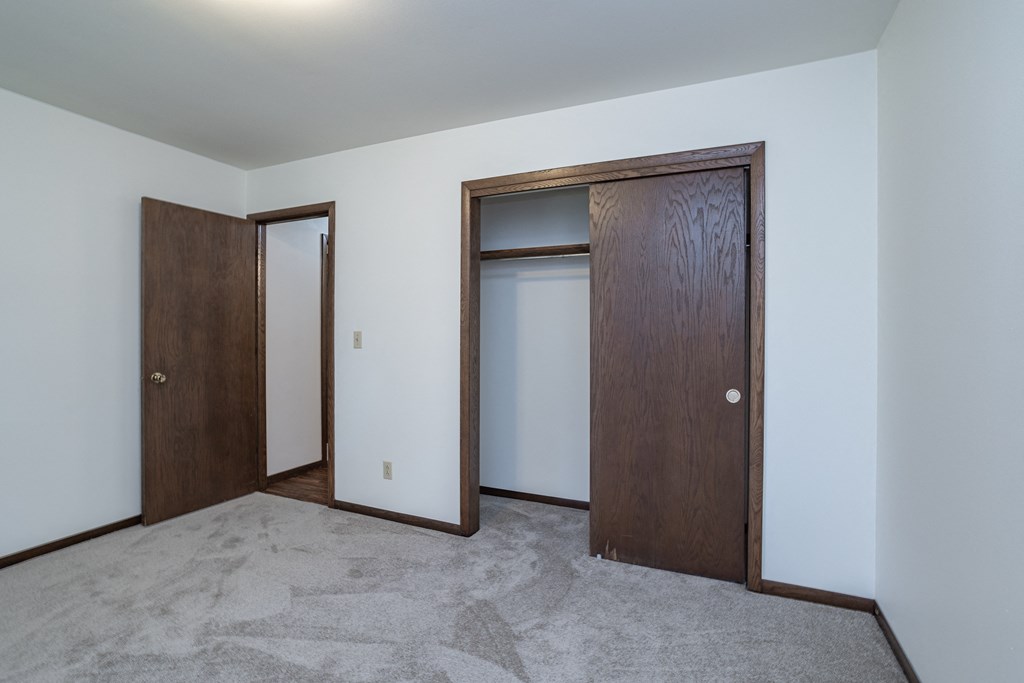 a bedroom with two doors and a carpet floor and white walls