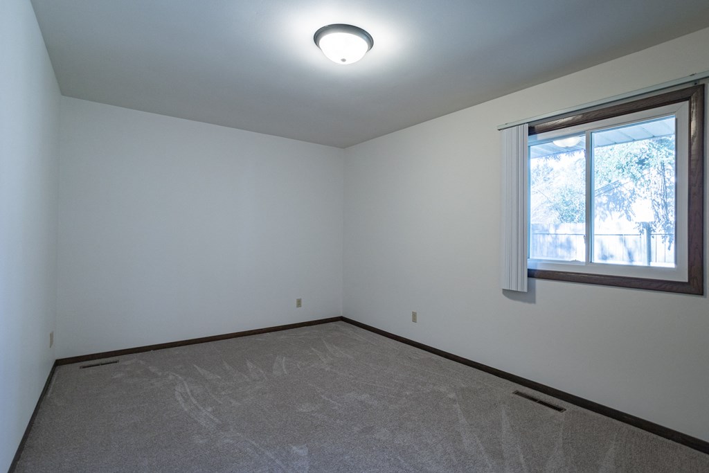 an empty room with a window and a carpet