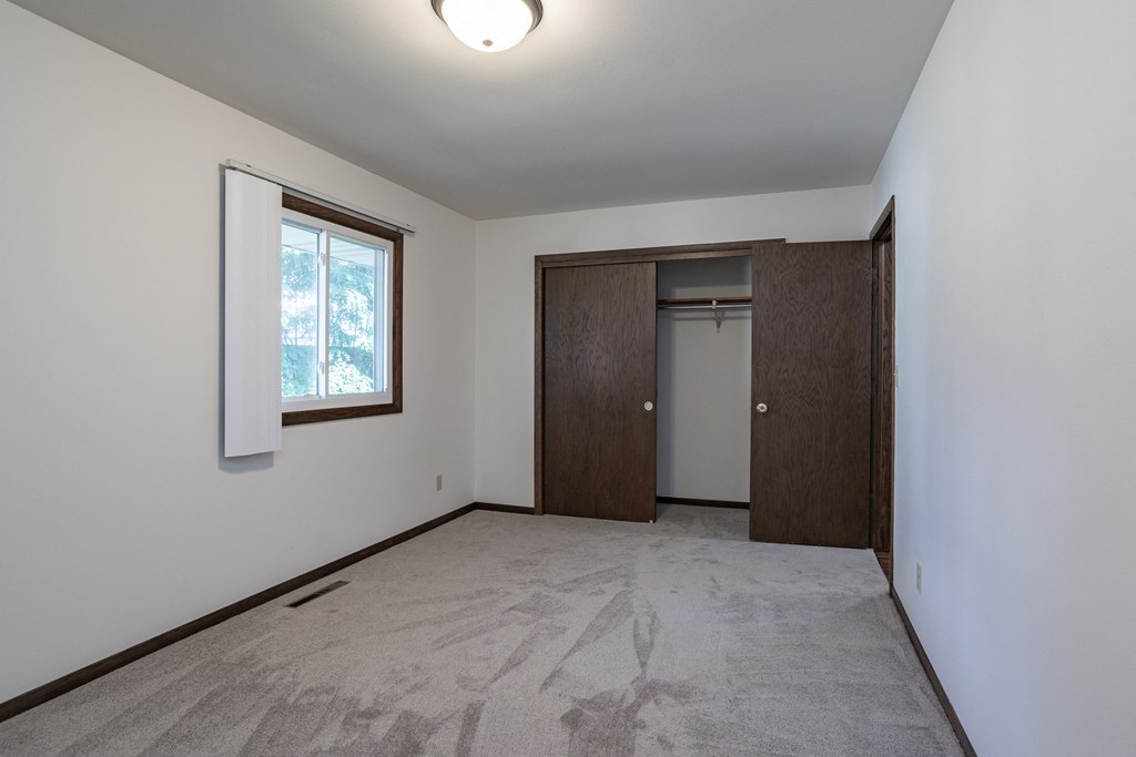 an empty living room with a door to a closet and a window