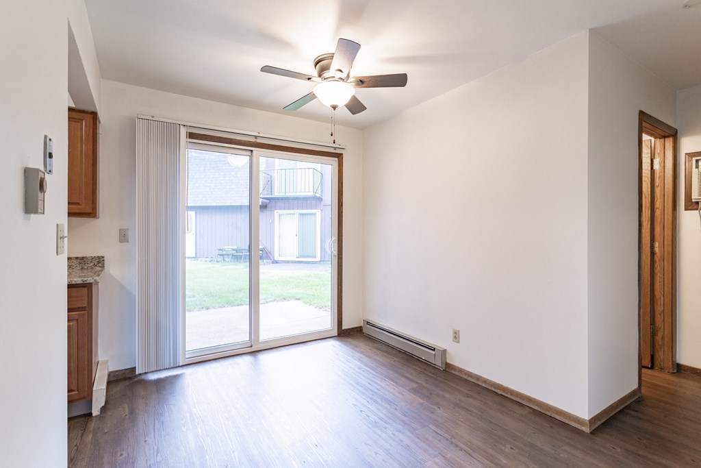 an empty living room with a ceiling fan and sliding glass door