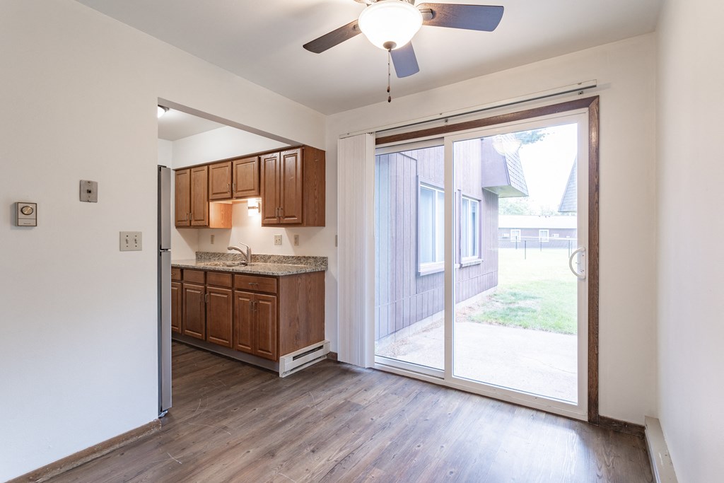 an empty living room with a sliding glass door to a kitchen