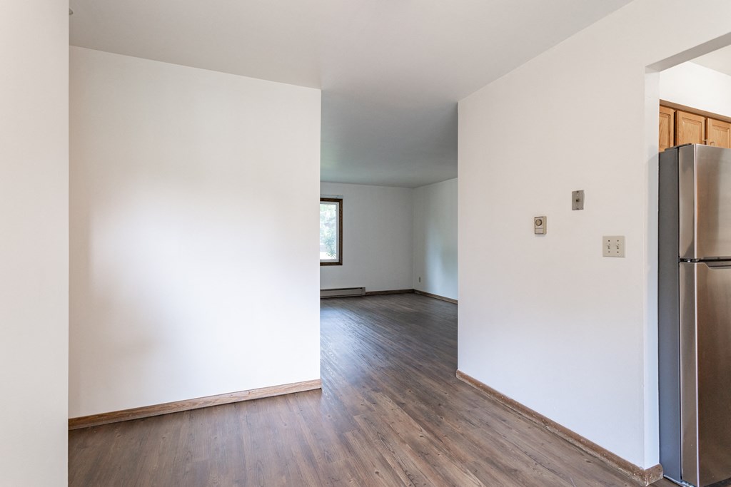 an empty living room with white walls and a refrigerator