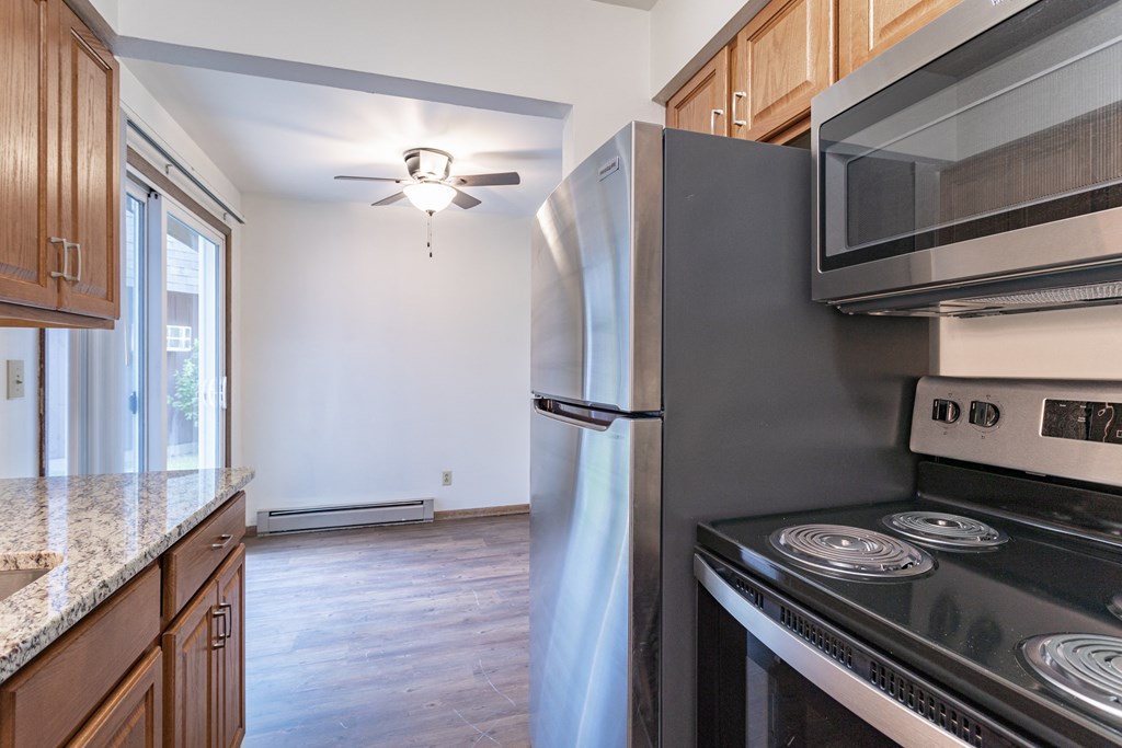 an empty kitchen with stainless steel appliances and wooden cabinets
