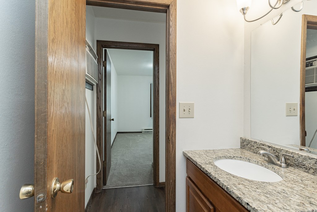 a bathroom with a sink and a mirror and a door to a hallway