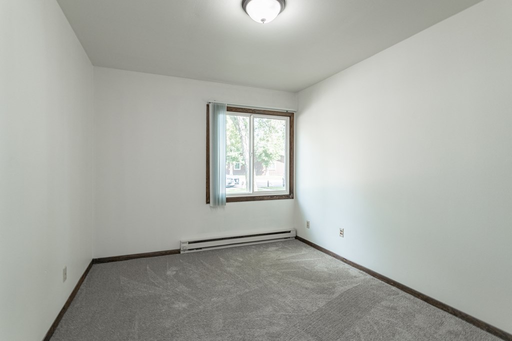 an empty living room with a window and white walls