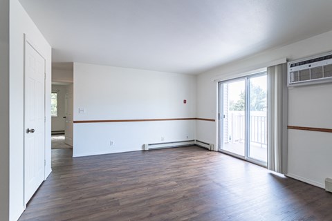 an empty living room with wood floors and white walls
