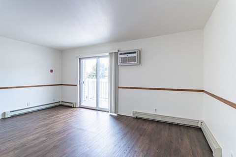 the living room of an empty home with wood floors and white walls
