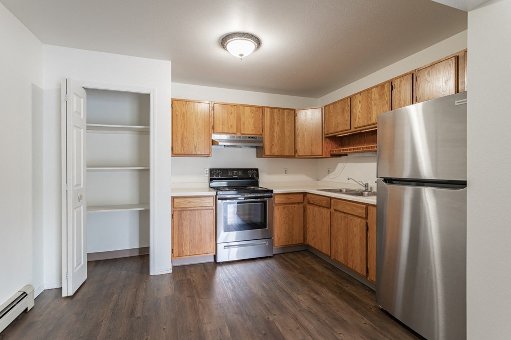 an empty kitchen with wooden cabinets and stainless steel appliances