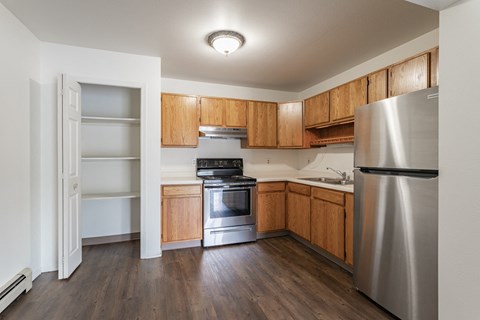 an empty kitchen with wooden cabinets and stainless steel appliances