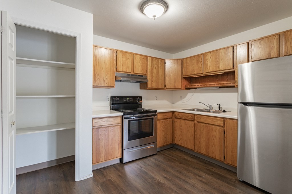 an empty kitchen with wooden cabinets and stainless steel appliances