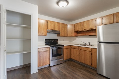 an empty kitchen with wooden cabinets and stainless steel appliances