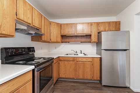 an empty kitchen with wooden cabinets and stainless steel appliances