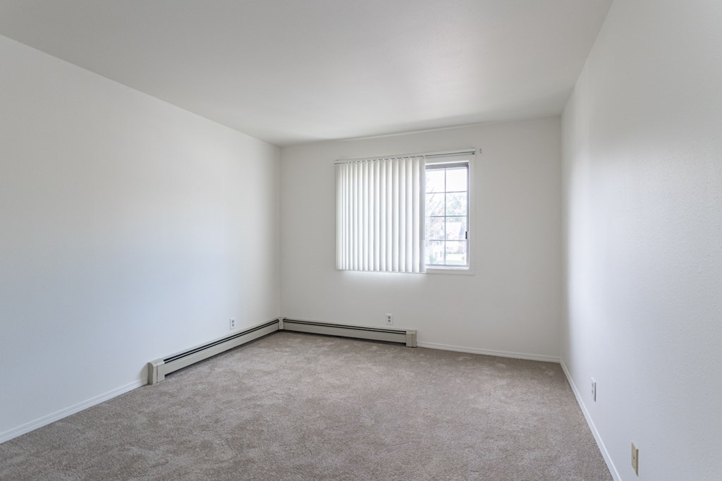 an empty room with a window and white walls