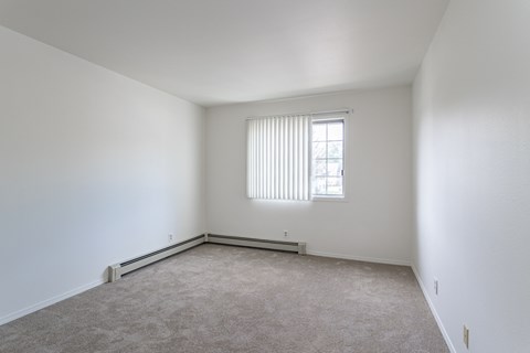 an empty room with a window and white walls