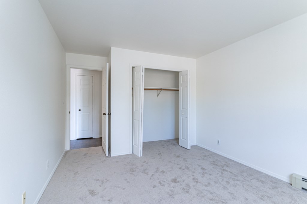 an empty living room with white walls and white doors and a closet