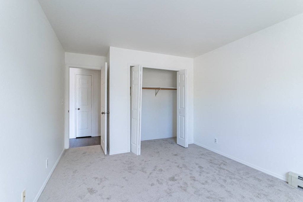 an empty room with white walls and doors and a closet
