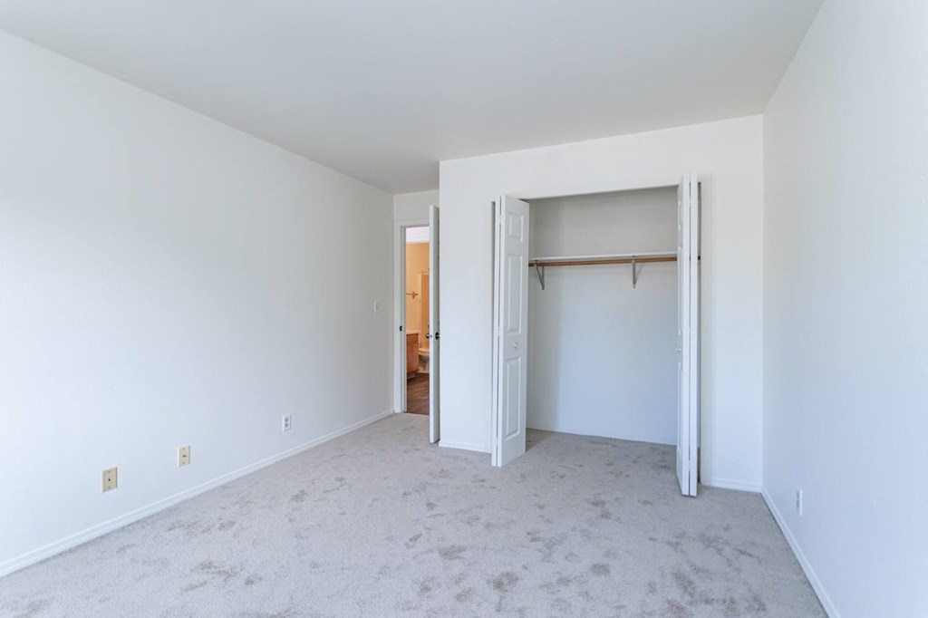 an empty living room with white walls and a closet